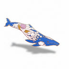 Decorative whale-shaped object on a textured surface with small plants and flowers.