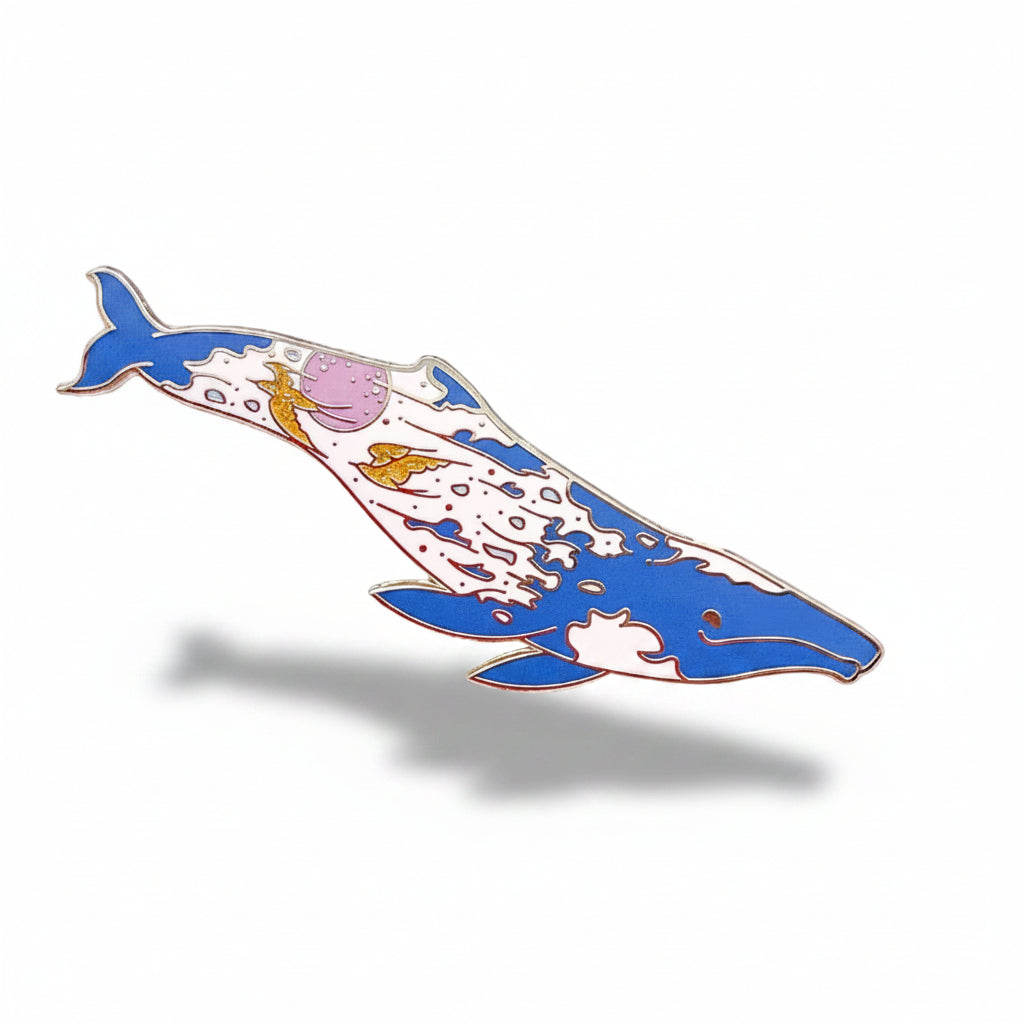 Decorative whale-shaped object on a textured surface with small plants and flowers.