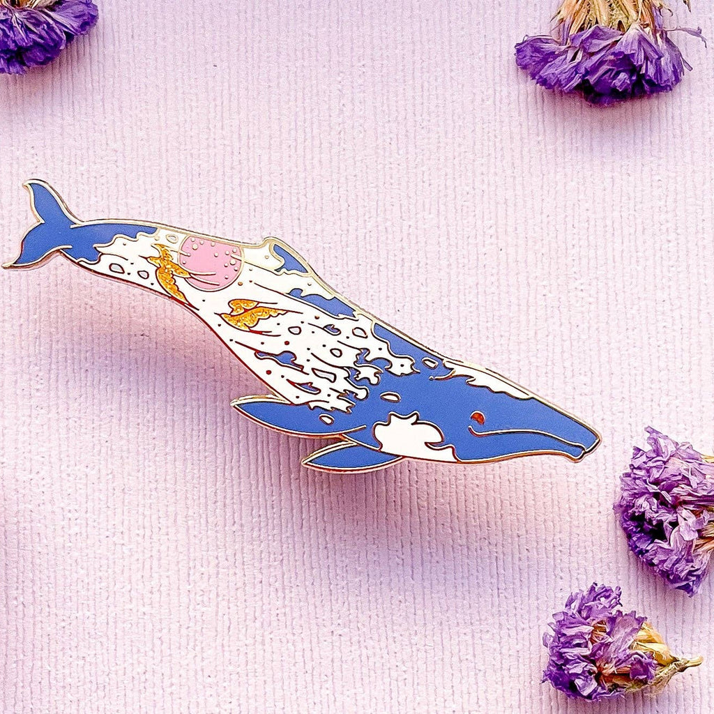 Decorative whale pin on a light pink background with dried flowers