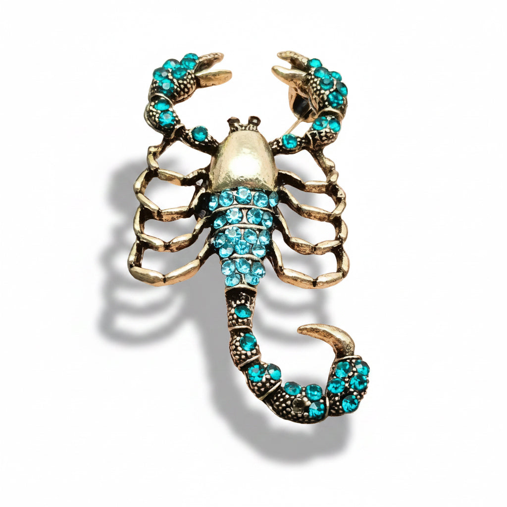 Scorpion-shaped brooch with turquoise stones on a white background