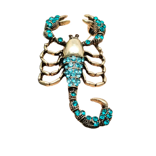 Scorpion-shaped brooch with turquoise stones on a white background