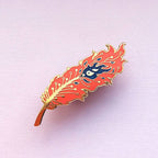 Decorative feather-shaped object with a blue center on a pink background