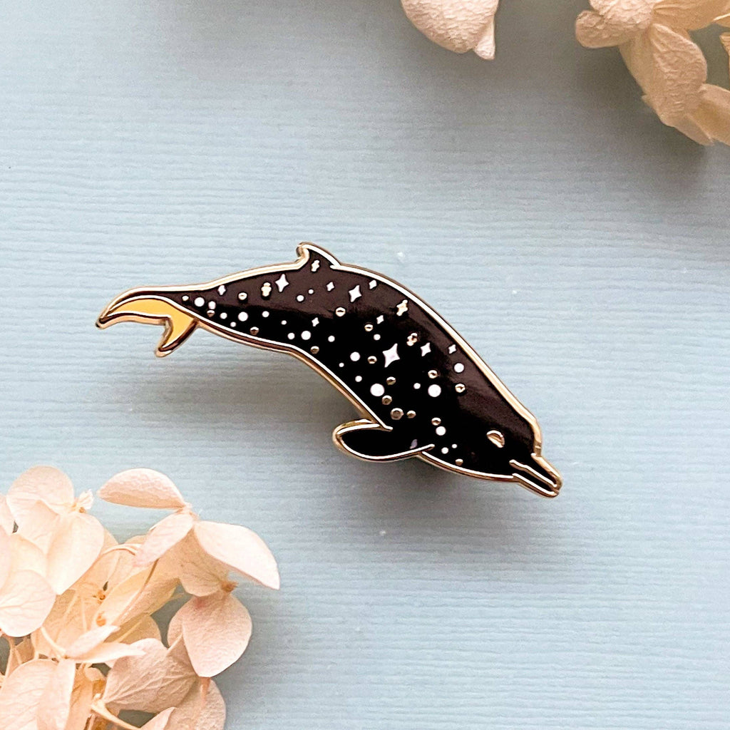 Dolphin-shaped pin on a light blue background with flowers