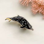 Dolphin-shaped pin on a light background with pink floral elements