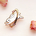 cosmic rabbit brooch with a crown on a light pink background with dried roses.