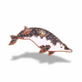 Decorative dolphin brooch with gemstones on a light background