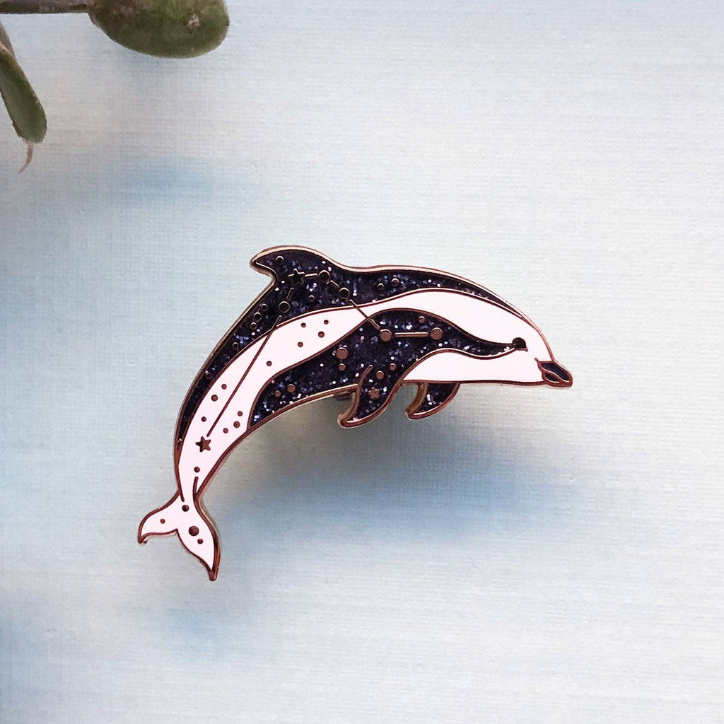 Dolphin-shaped pin on a light blue background with leaves