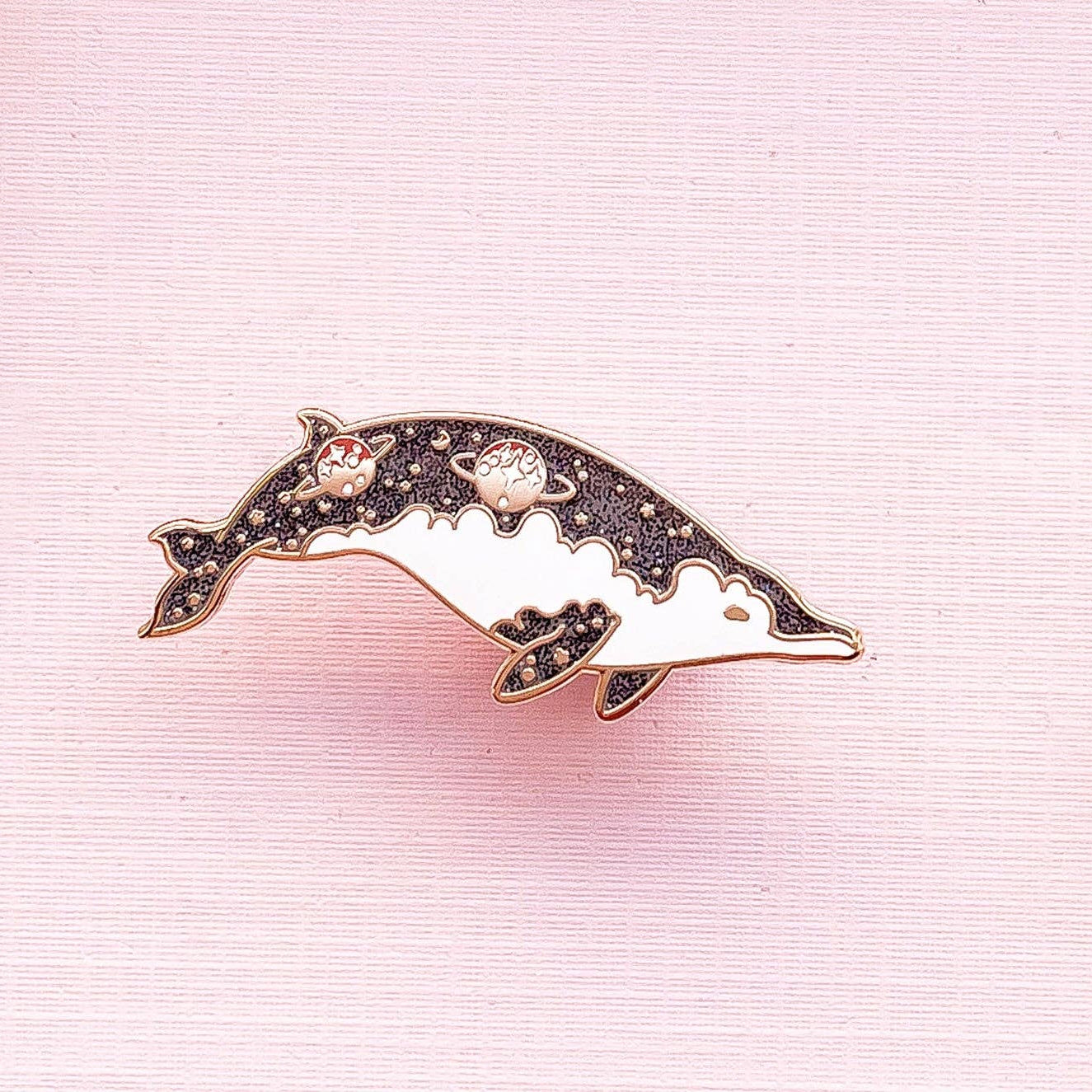 Dolphins-shaped brooch with floral details on a pink background