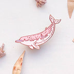 Decorative pink dolphin figure on a white surface with dried flowers and leaves.