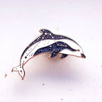 Dolphin-shaped brooch with blue accents on a white background