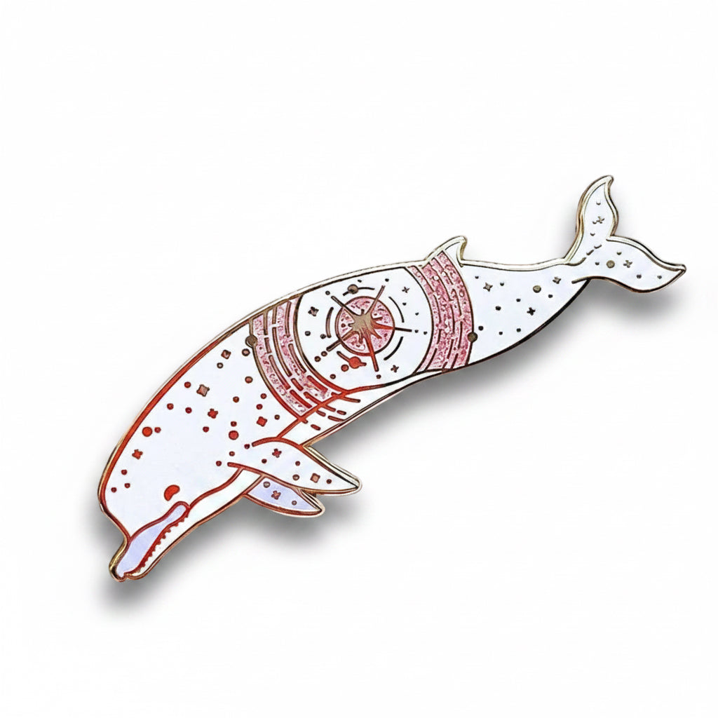 Decorative brooch with a whale design on a textured white background