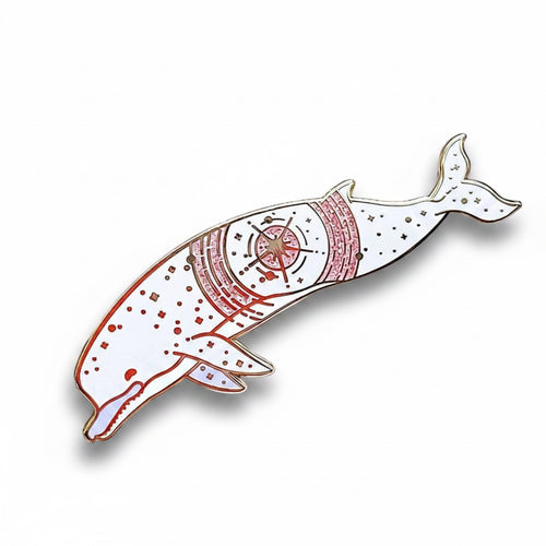 Decorative brooch with a whale design on a textured white background