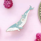 Decorative whale-shaped object on a pink background with flowers