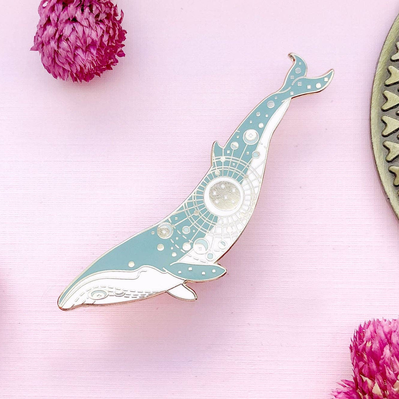 Decorative whale-shaped object on a pink background with flowers