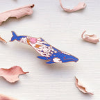 Decorative whale figurine on a textured white surface with pink petals