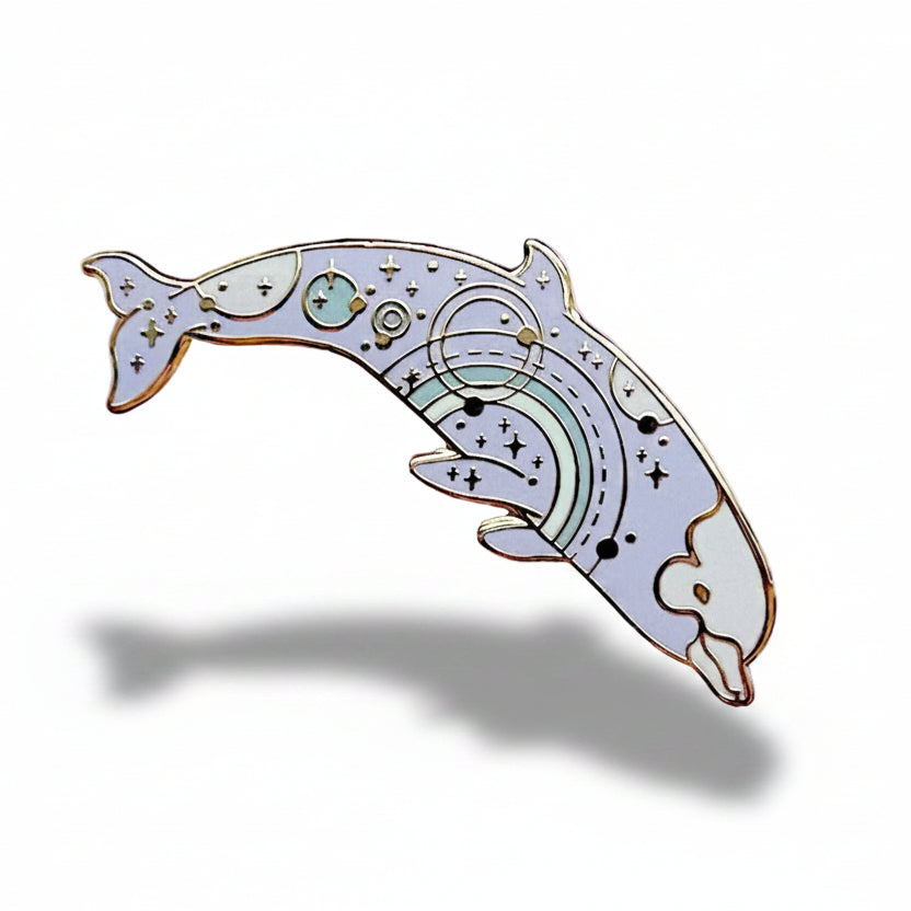 Decorative dolphin pin with rainbow design on a light pink background with dried flowers.