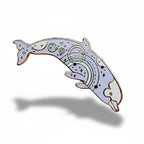 Decorative dolphin pin with rainbow design on a light pink background with dried flowers.
