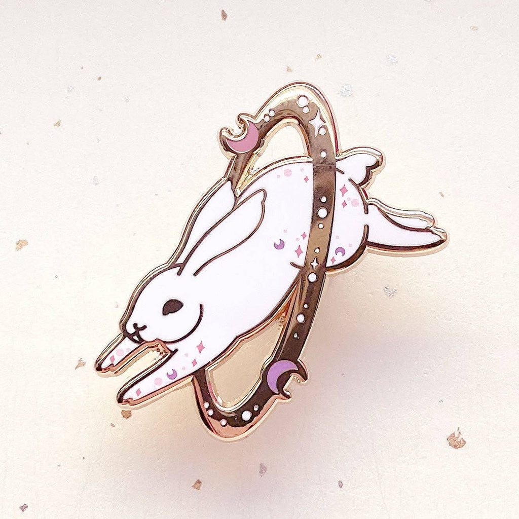 Enamel pin of a white rabbit with a pink bow on a light background