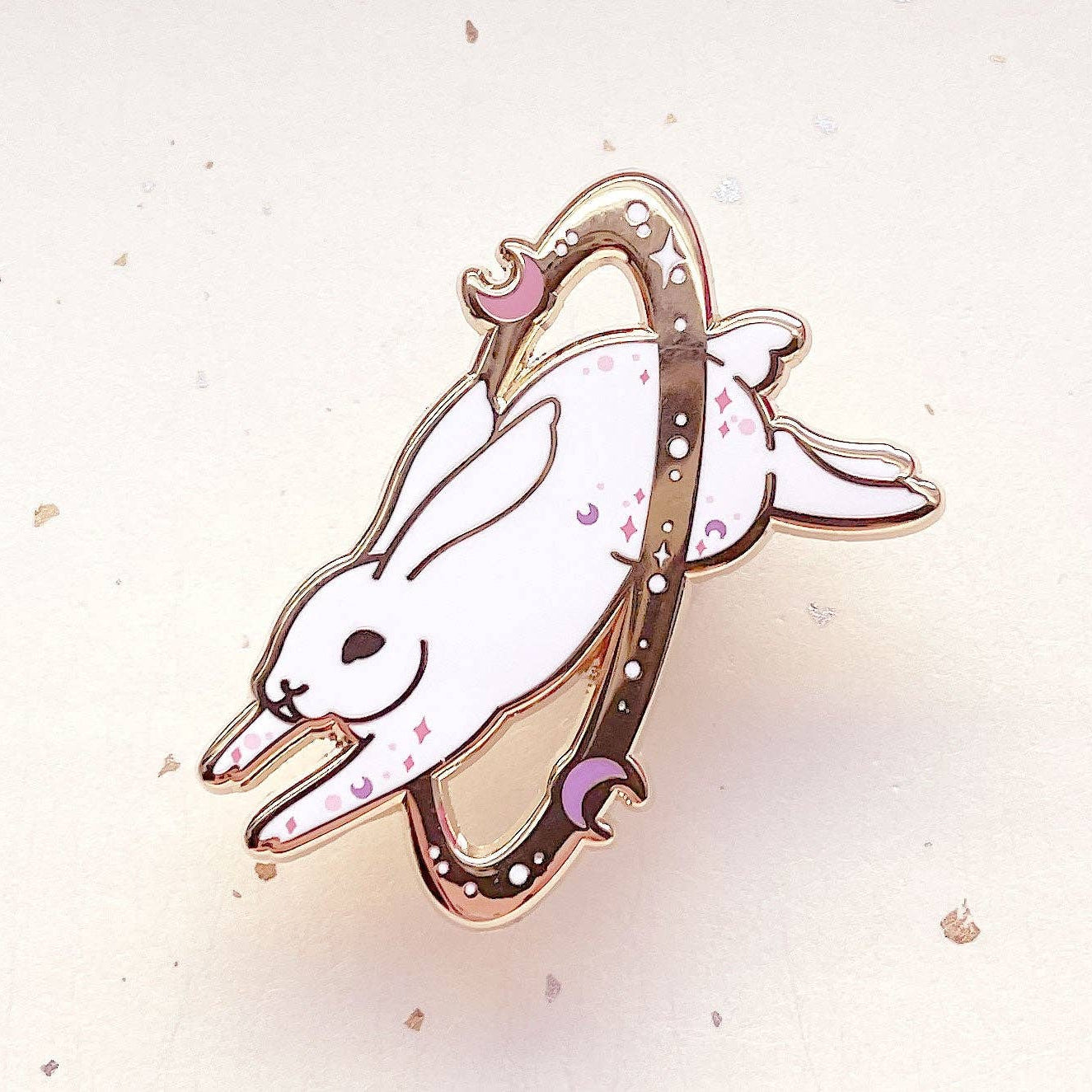 Enamel pin of a white rabbit with a pink bow on a light background