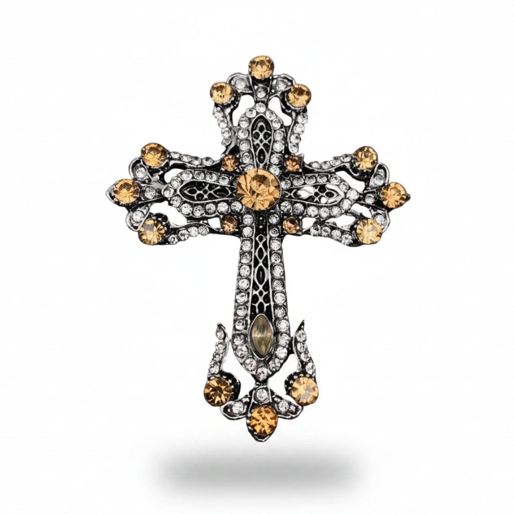 Decorative cross brooch with gemstones on a gray textured background