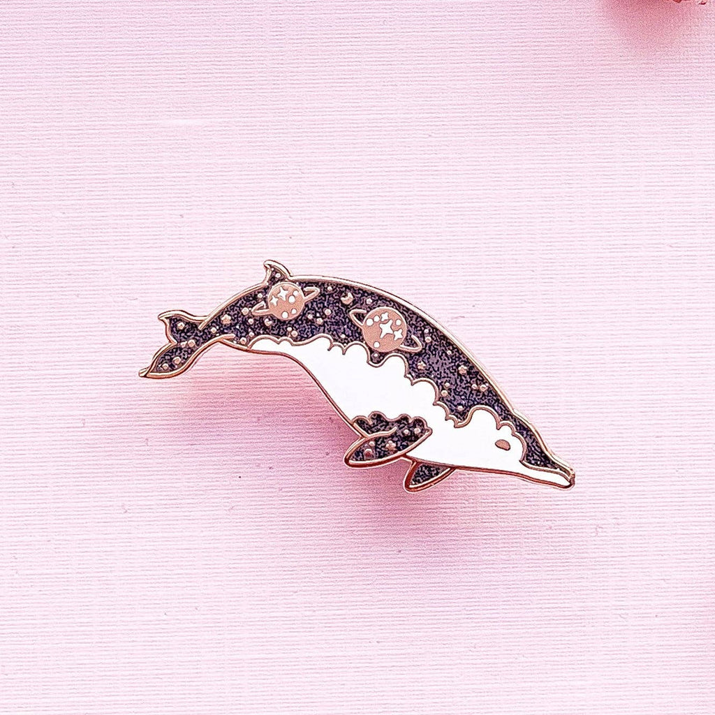 Dolphin-shaped brooch with pink accents on a pink background