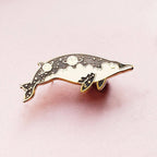 Dolphin-shaped pin on a pink background