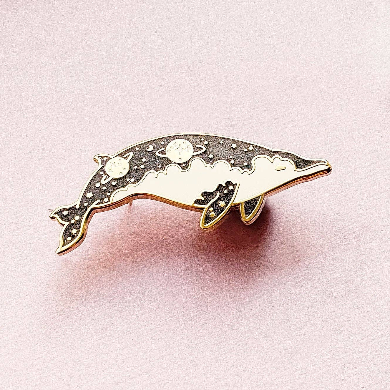 Dolphin-shaped pin on a pink background