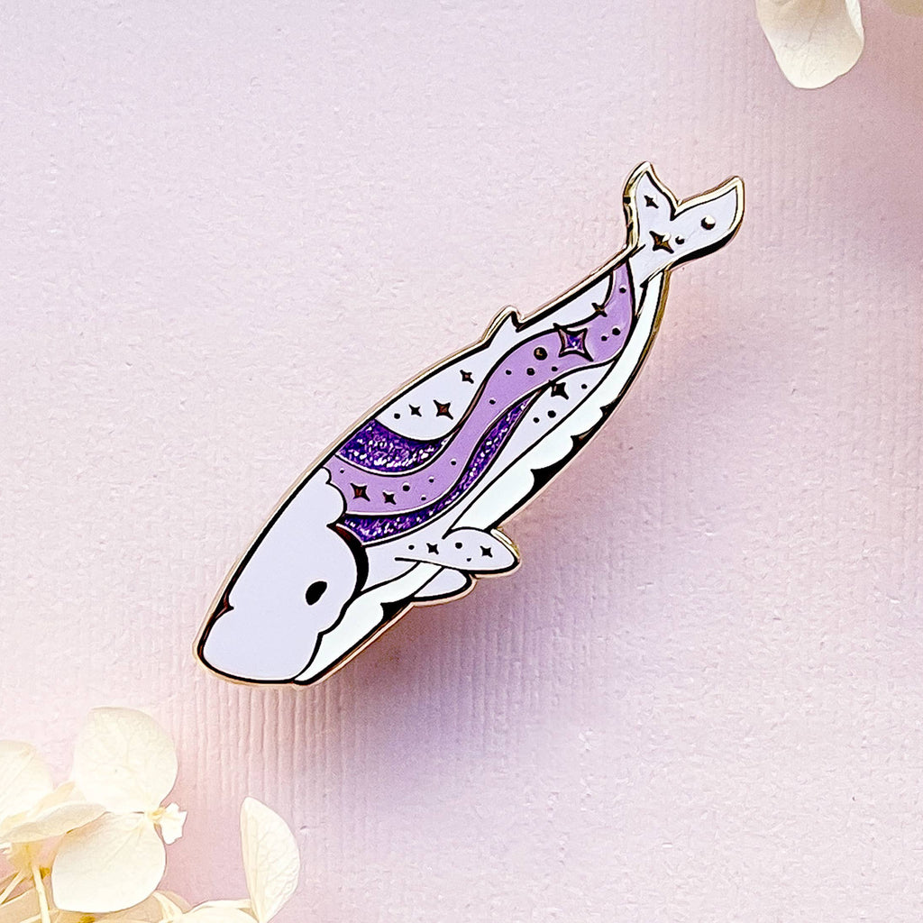 Decorative feather pin with purple design on a light pink background with flowers