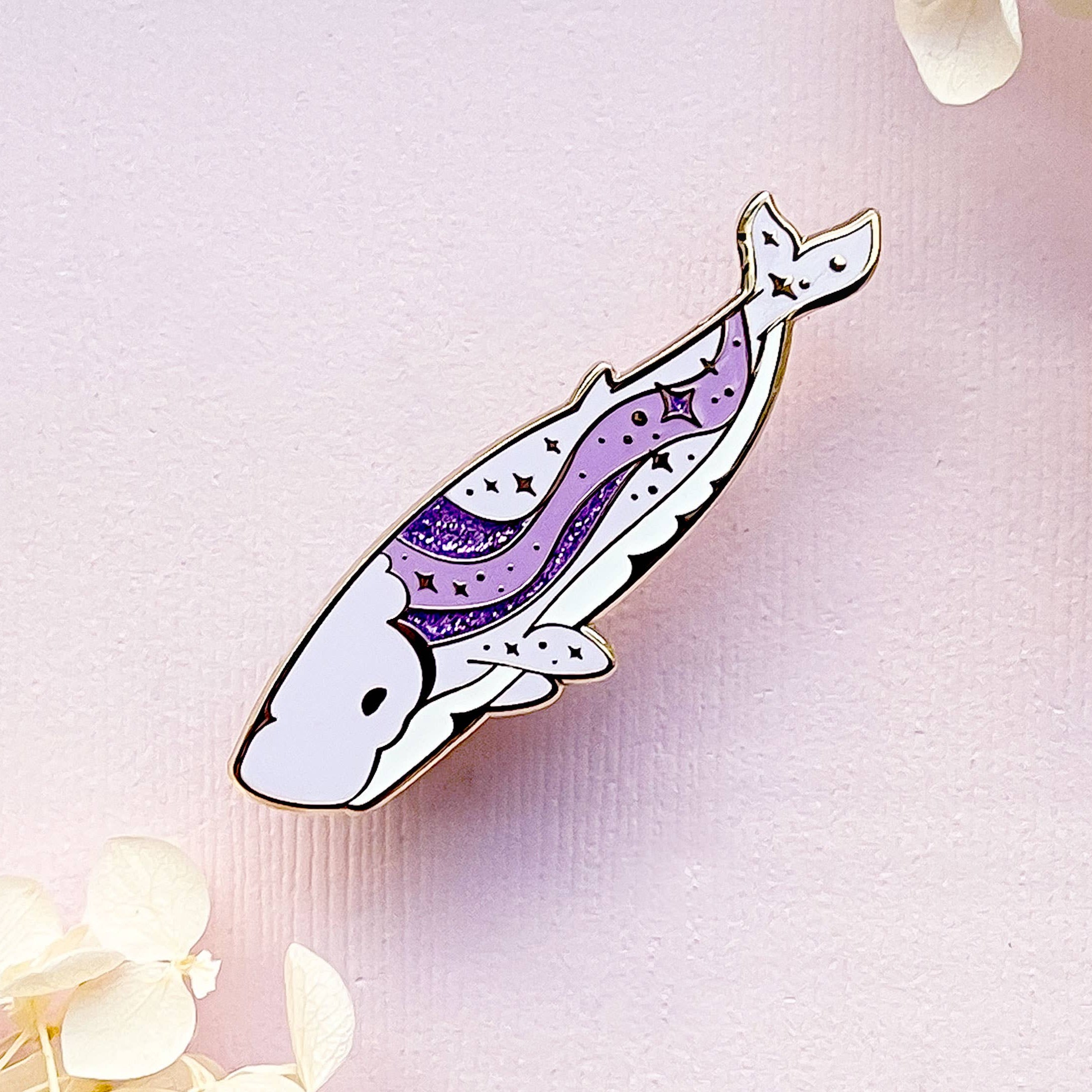 Decorative feather pin with purple design on a light pink background with flowers