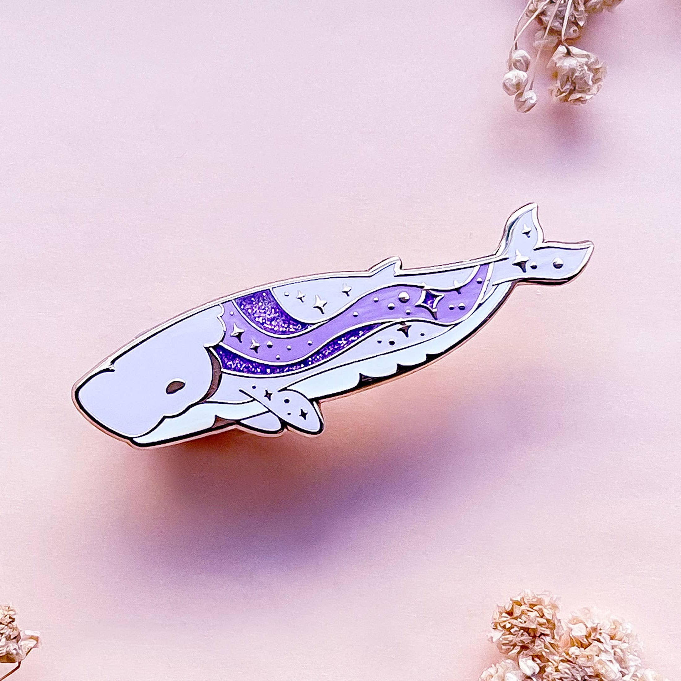 Decorative whale-shaped object with a purple design on a soft pink background