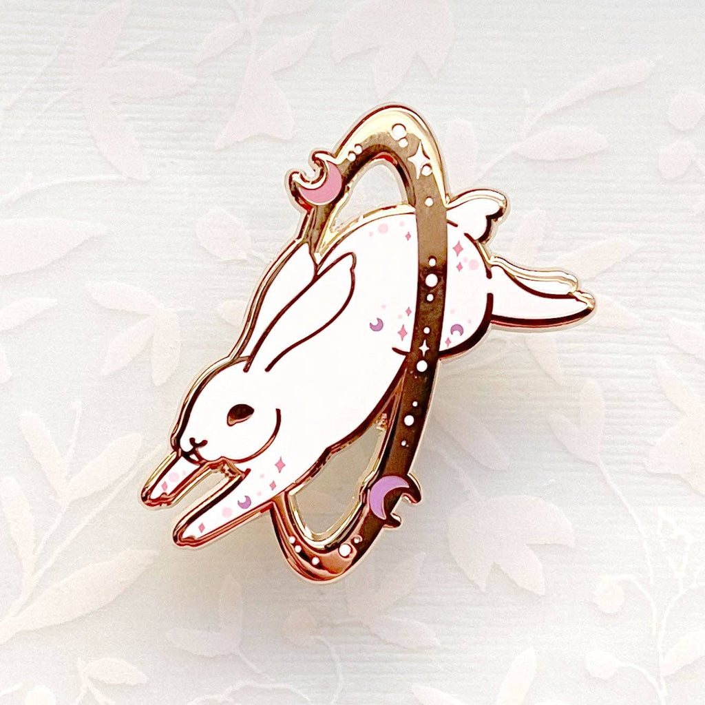 Enamel pin of a white rabbit with pink accents on a soft white background