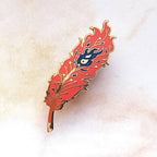 Feather-shaped pin with flame design on a textured beige background