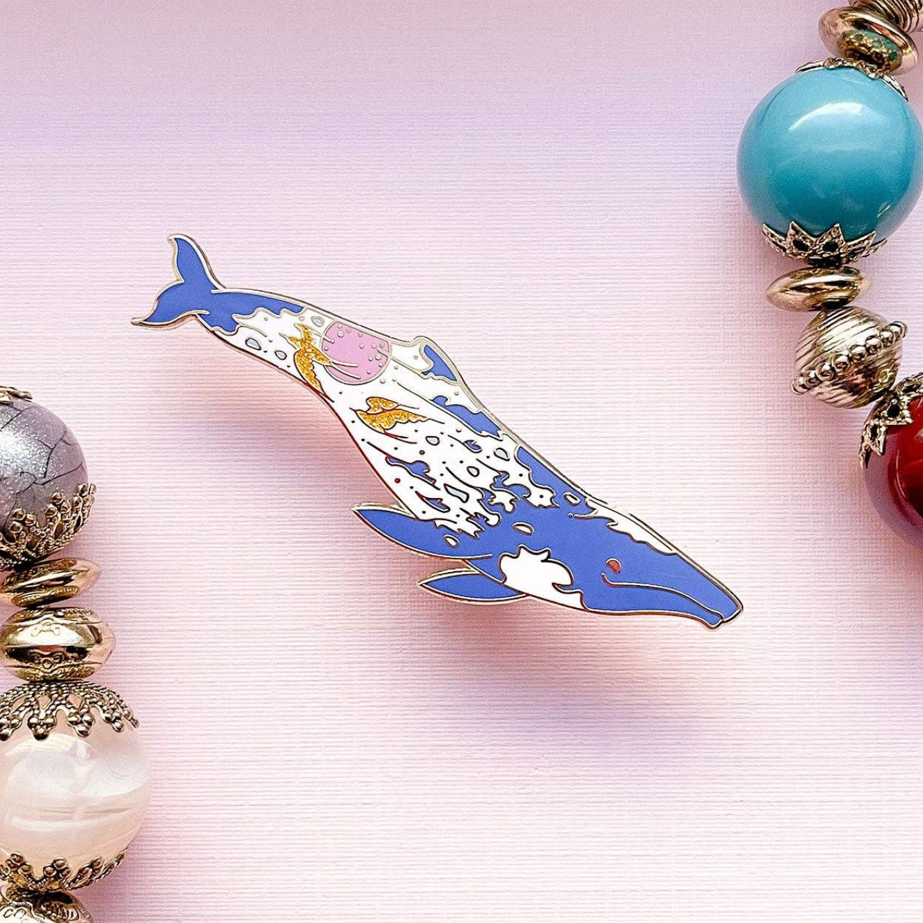 Bracelet with colorful beads and a dolphin charm on a pink background