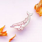 Decorative lapel pin with floral elements on a light pink background
