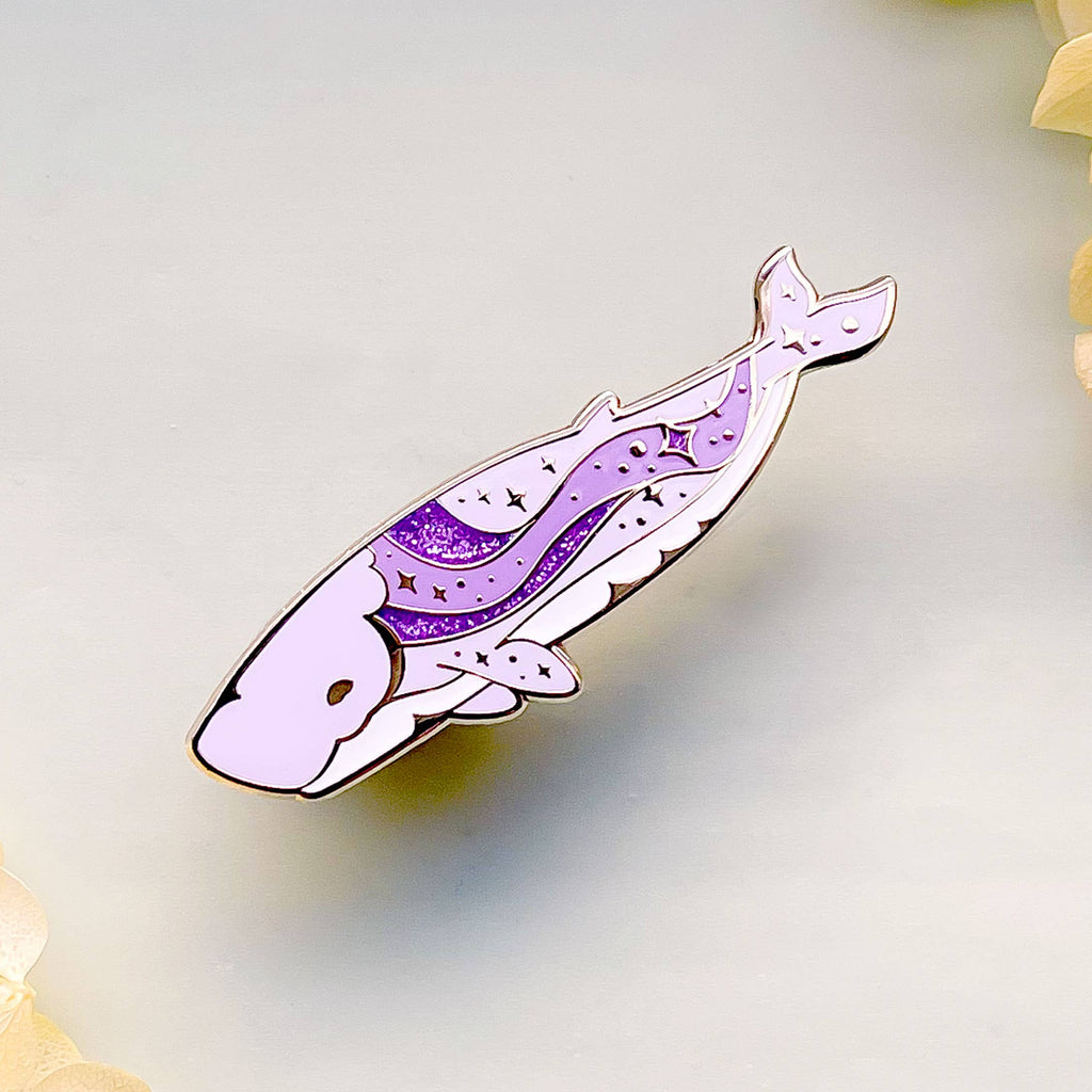 Decorative whale-shaped pin with purple design on a light background