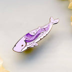 Decorative whale-shaped pin with purple design on a light background