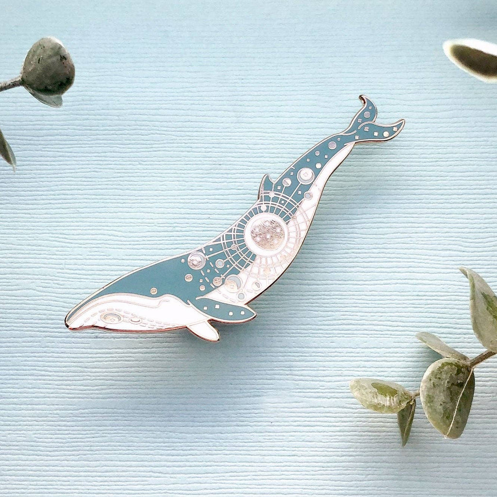 Decorative whale-shaped object on a light blue background with eucalyptus leaves.