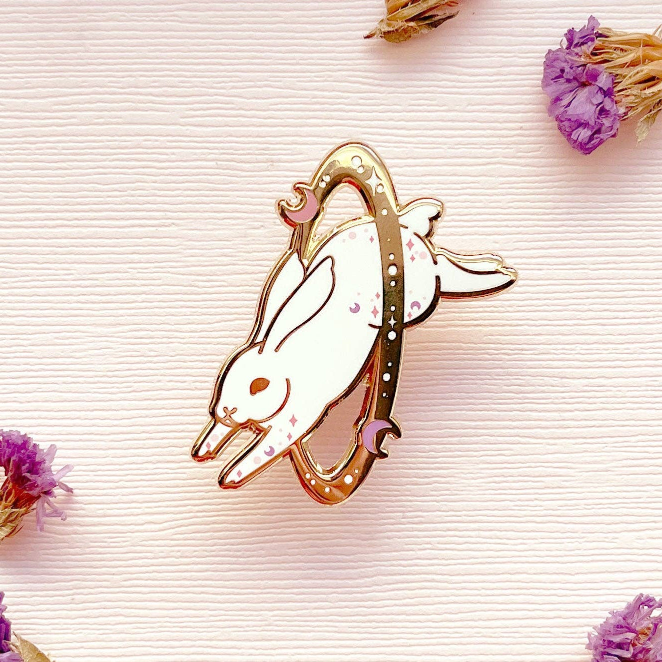 Decorative bunny-shaped object on a textured surface with dried flowers