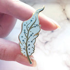 Hand holding a decorative Pegasus pin with a marble background