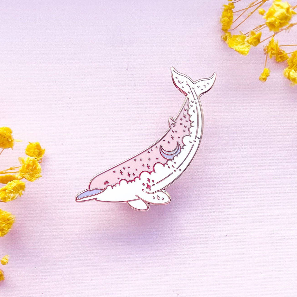 Decorative lapel pin of a dolphin with floral elements on a light pink background