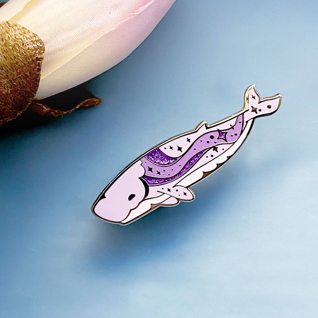 Decorative whale-shaped pin on a light blue background