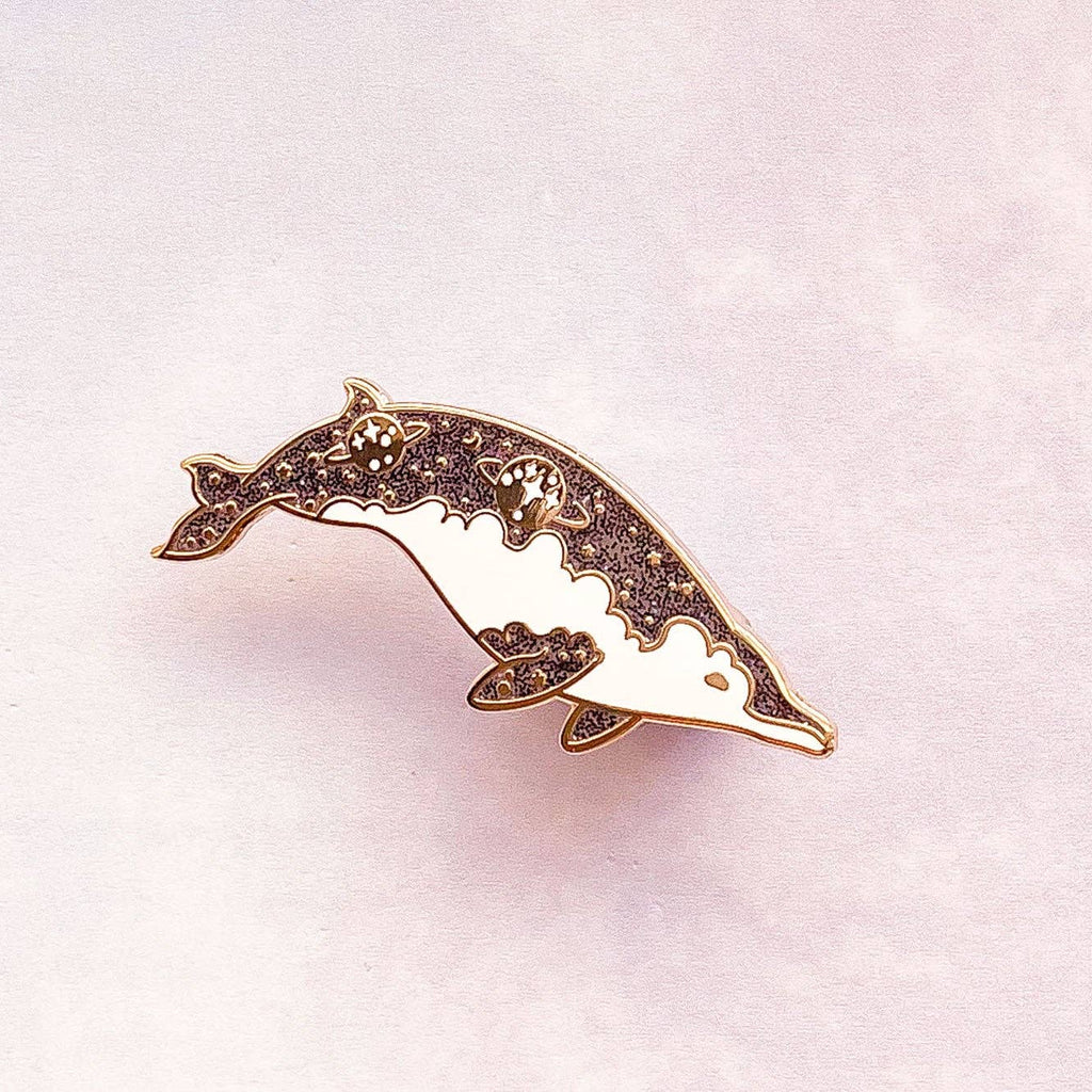 Detailed dolphin-shaped pin on a light pink background