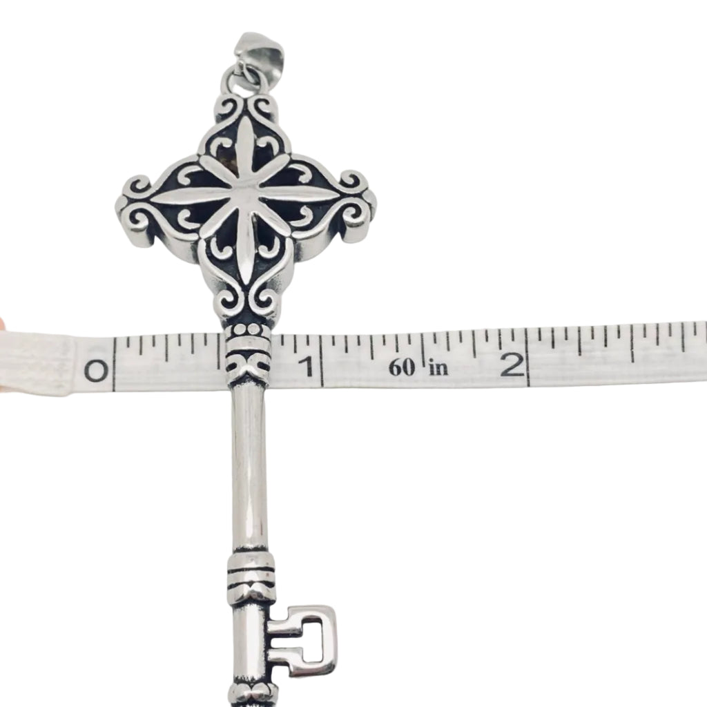 Decorative stainless steel 316L Key Pendant with intricate designs on a white background, measured against a ruler.
