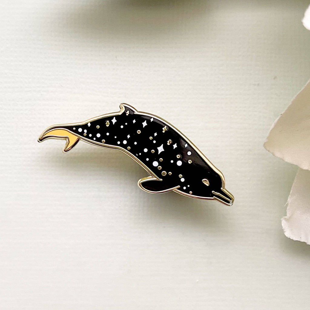 Dolphin-shaped pin with star pattern on a white background