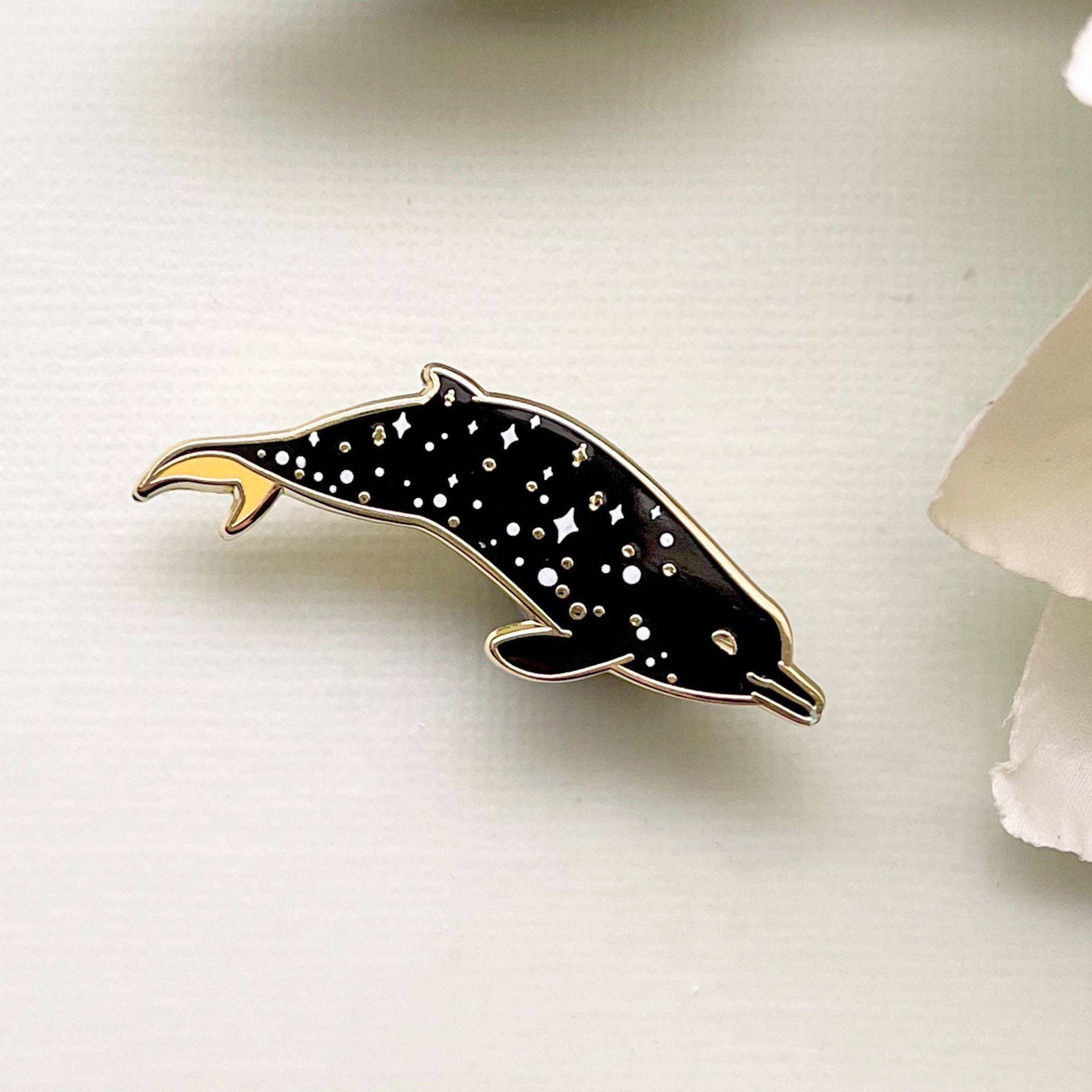 Dolphin-shaped pin with star pattern on a white background