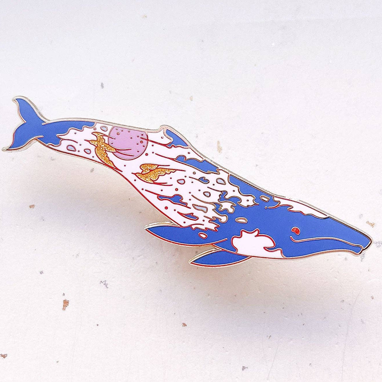 Colorful whale-shaped pin on a white background