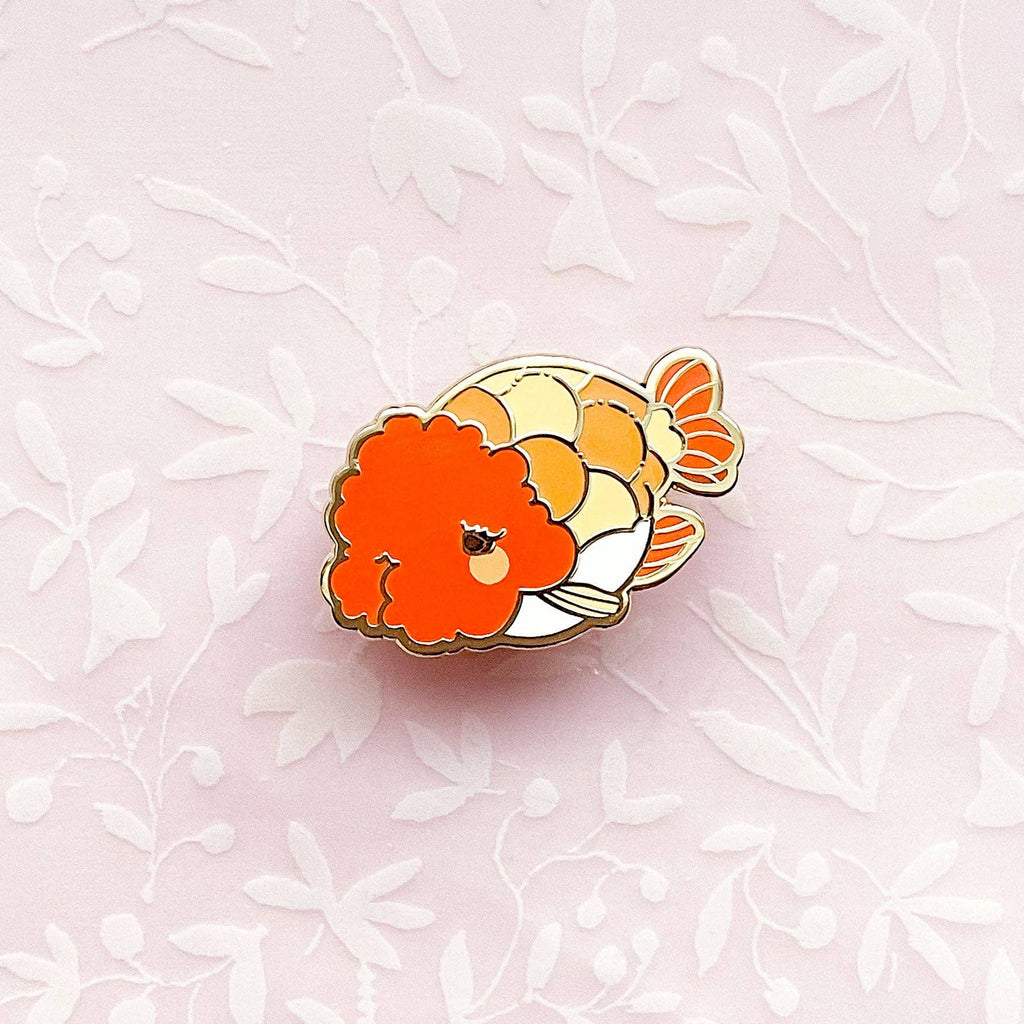 Ranchu Goldfish enamel pin on a light pink floral background