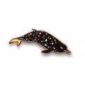 Dolphin-shaped pin with star pattern held between fingers on a light background