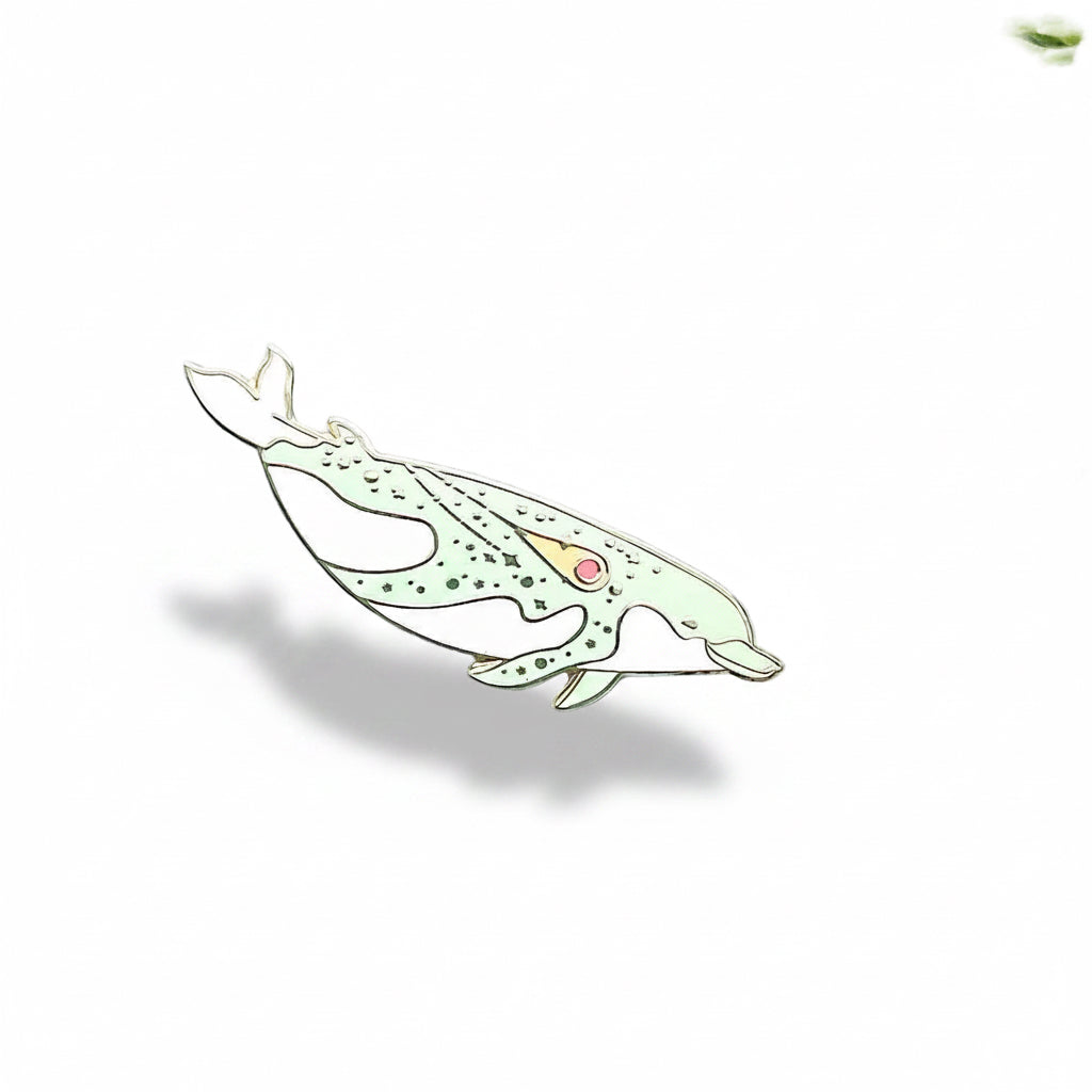 Dolphin-shaped brooch on a light blue background with green leaves