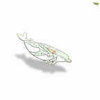 Dolphin-shaped brooch on a light blue background with green leaves